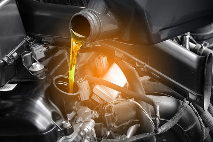 Un envase de aceite vierte lubricante 0W-8 en el cárter de un vehículo